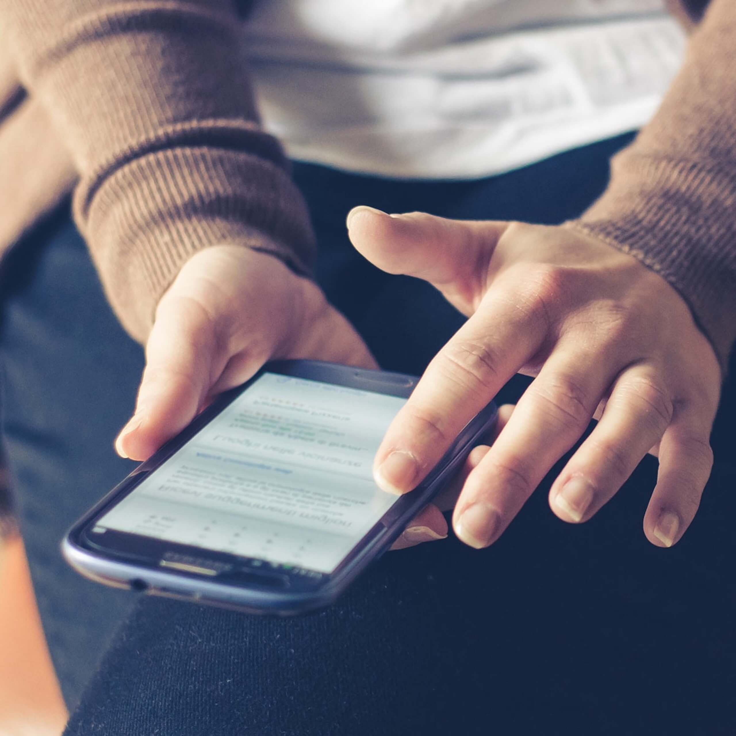 Person Holding Smartphone While Sitting